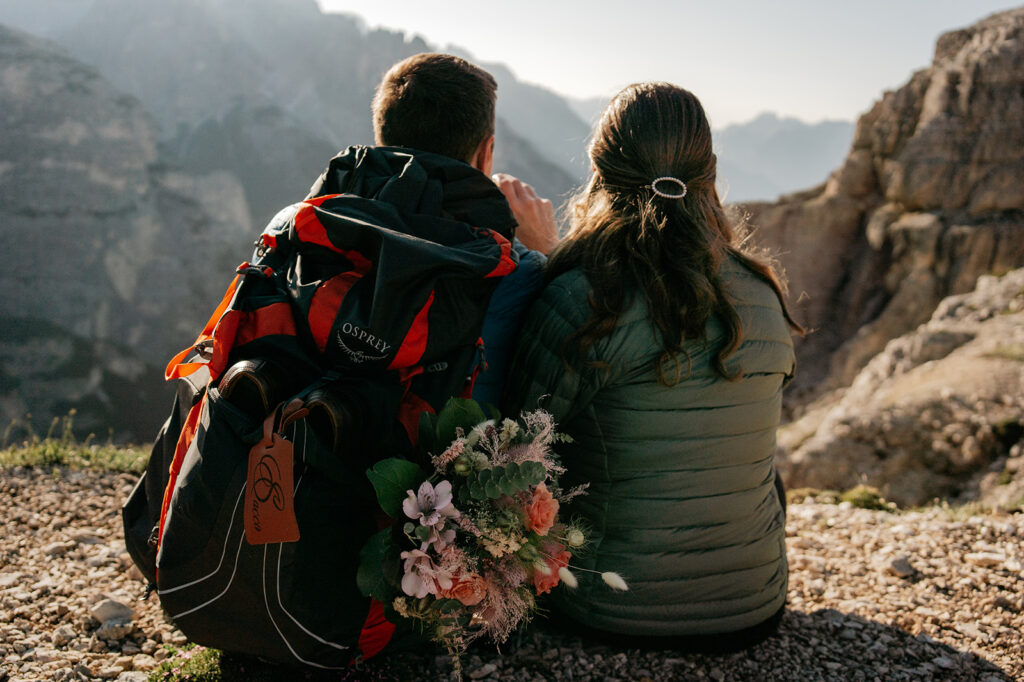 Couple sitting with backpack overlooking mountains.