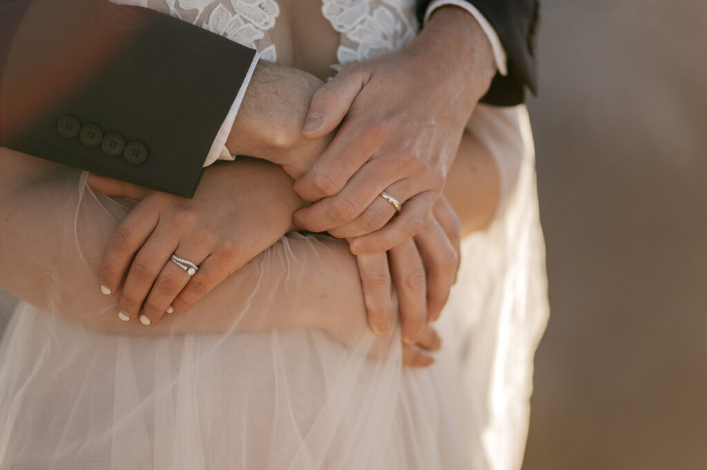 Couple holding hands with wedding rings visible.