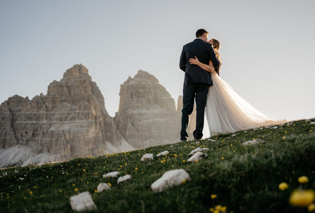 Couple embracing on mountain landscape during sunset.