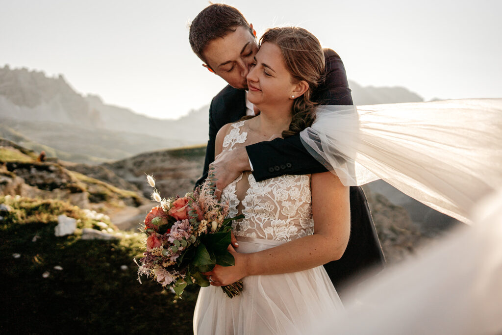 Bride and groom embrace during mountain wedding