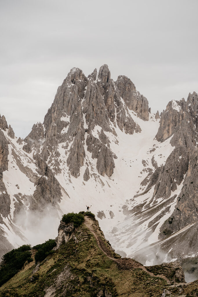 Person standing triumphantly on snowy mountain peak.