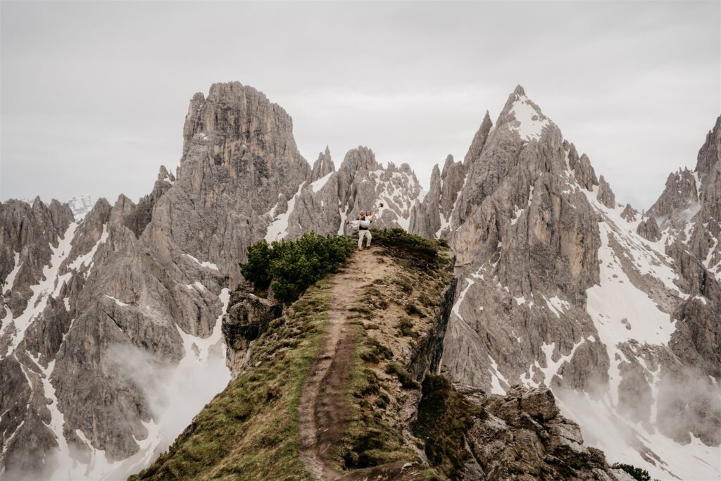 Person on mountain path with dramatic peaks background.