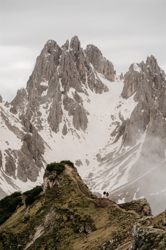 Hikers on snowy mountain path with cloudy sky