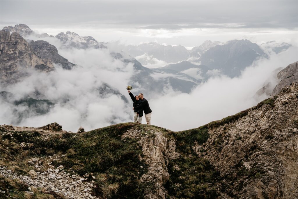 Couple celebrates atop misty mountain peak.