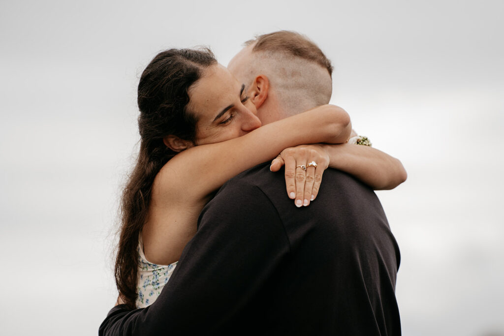 Couple hugging, woman wearing engagement ring.