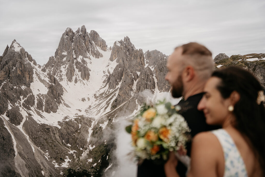 Couple with bouquet overlooking snowy mountains