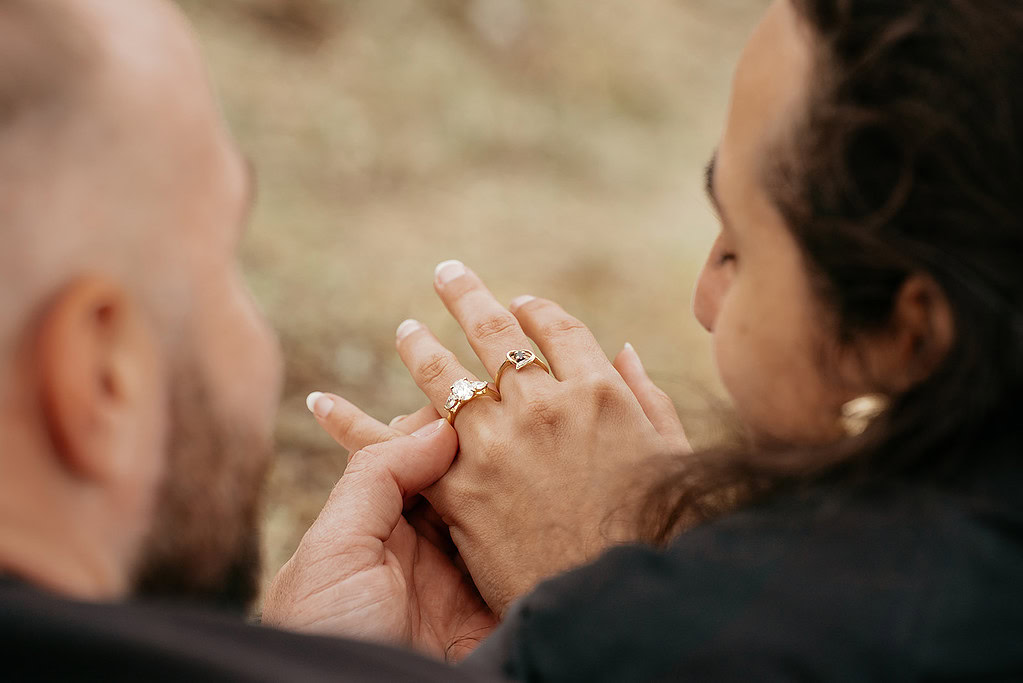 Couple holding hands with engagement rings