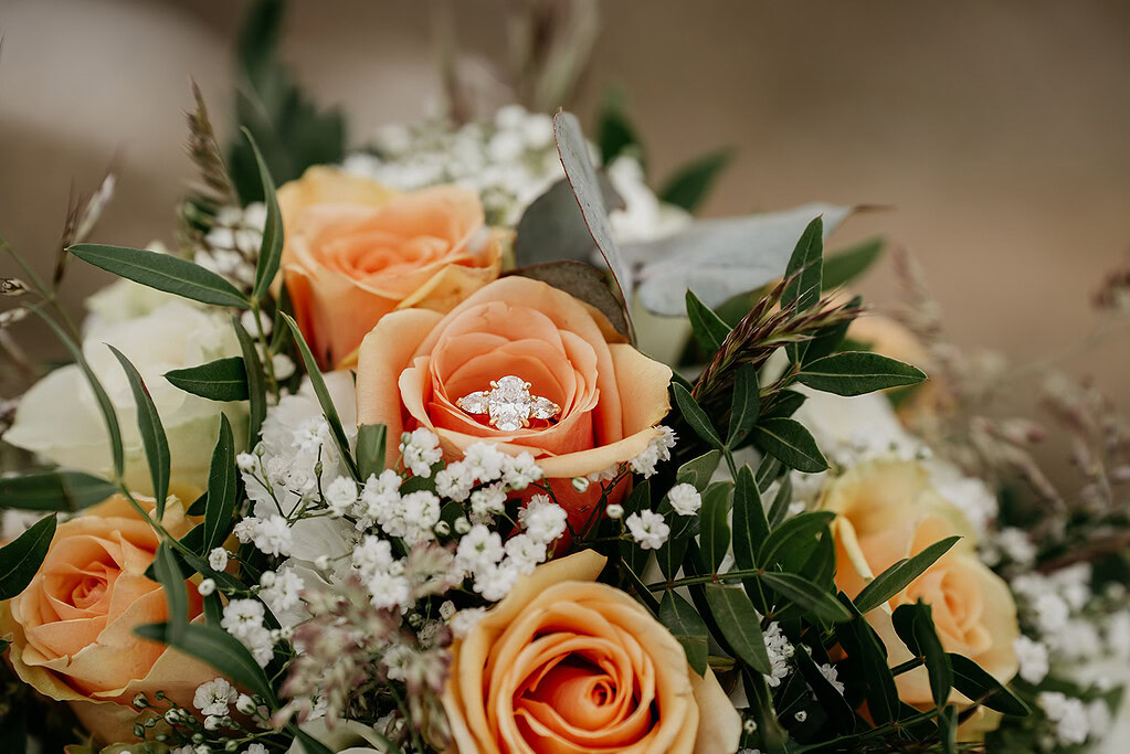 Engagement ring on orange roses bouquet