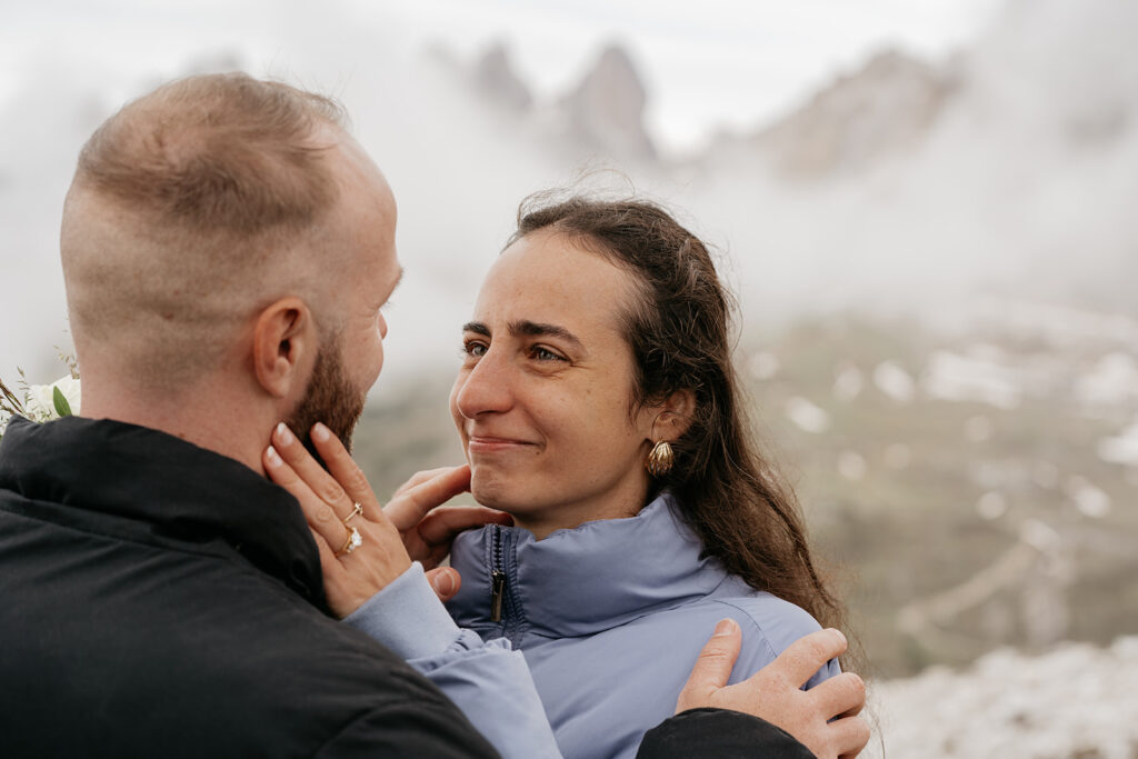 Couple embracing outdoors in a foggy landscape.