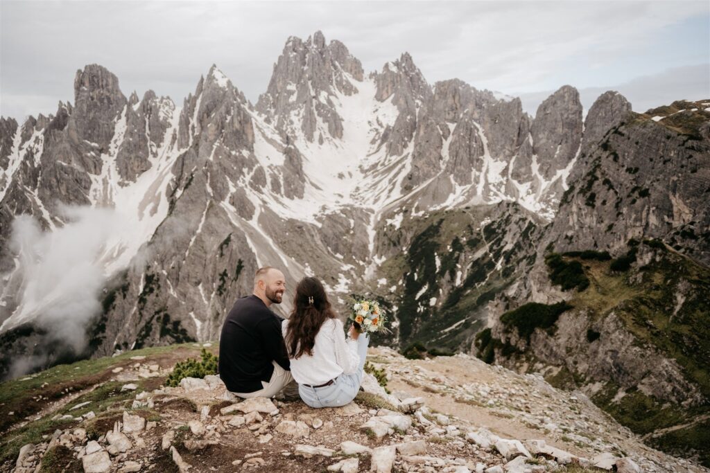 Couple sitting, enjoying scenic mountain view.