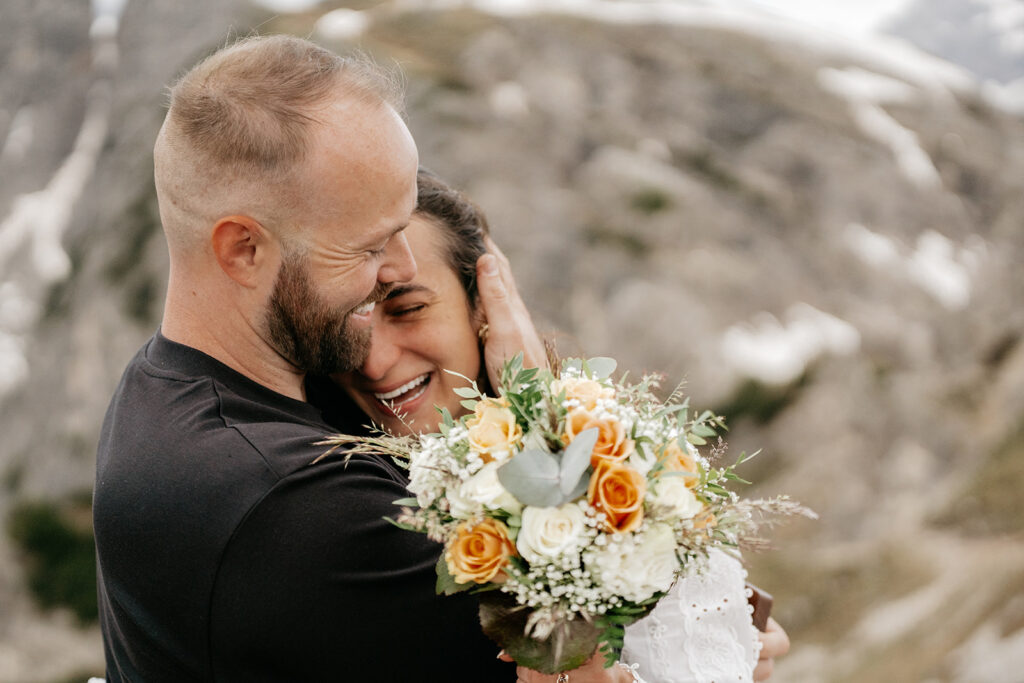 Couple embracing with a floral bouquet outdoors.