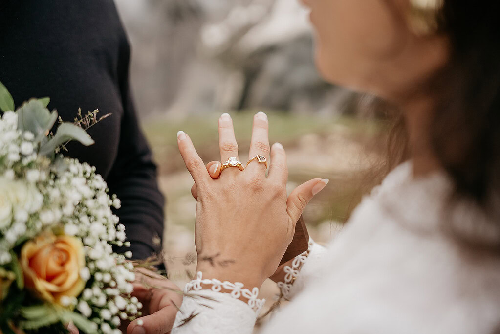 Bride showing engagement and wedding rings with bouquet