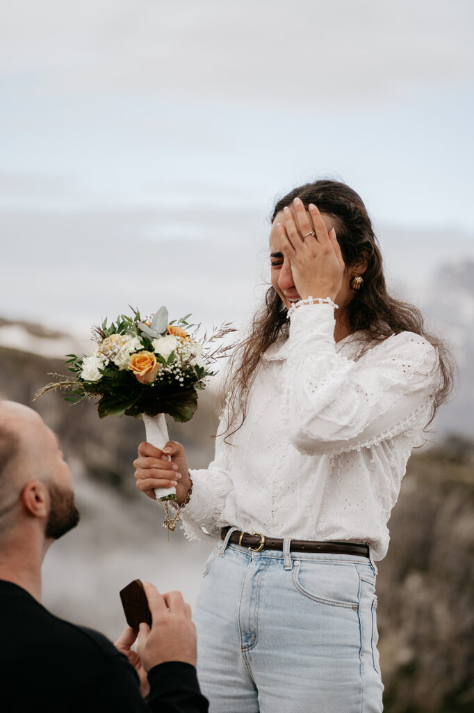 Man proposing, woman with flowers, emotional reaction