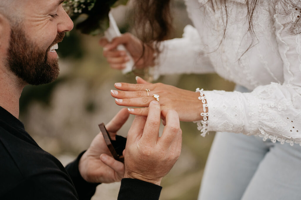 Man proposing, placing ring on woman's finger.