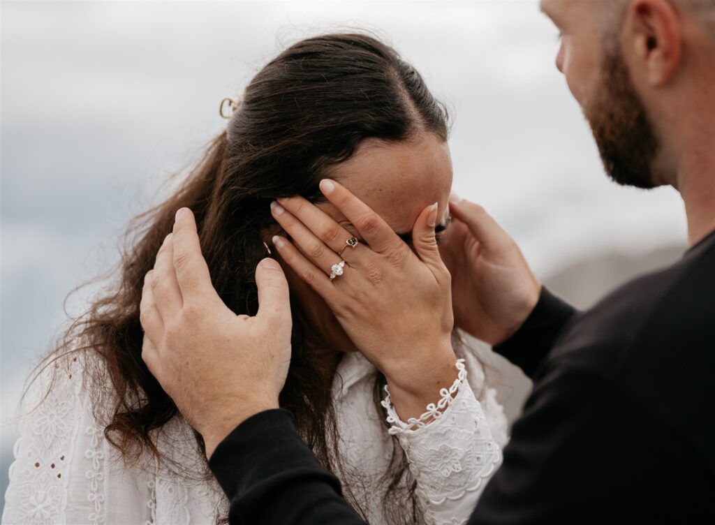 Woman covering face, emotional moment, engagement ring shown