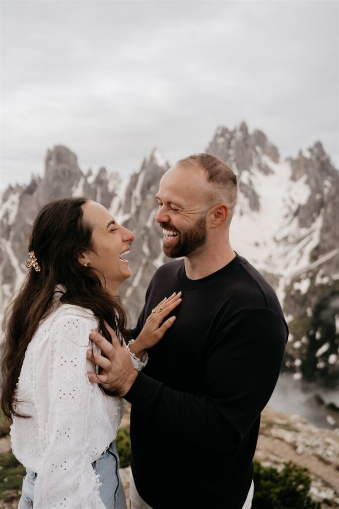 Couple laughing with snowy mountains in background.