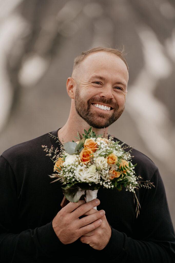 Smiling man holding a bouquet of flowers.