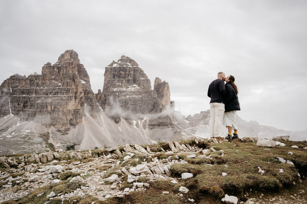 Couple kissing by dramatic mountain landscape.