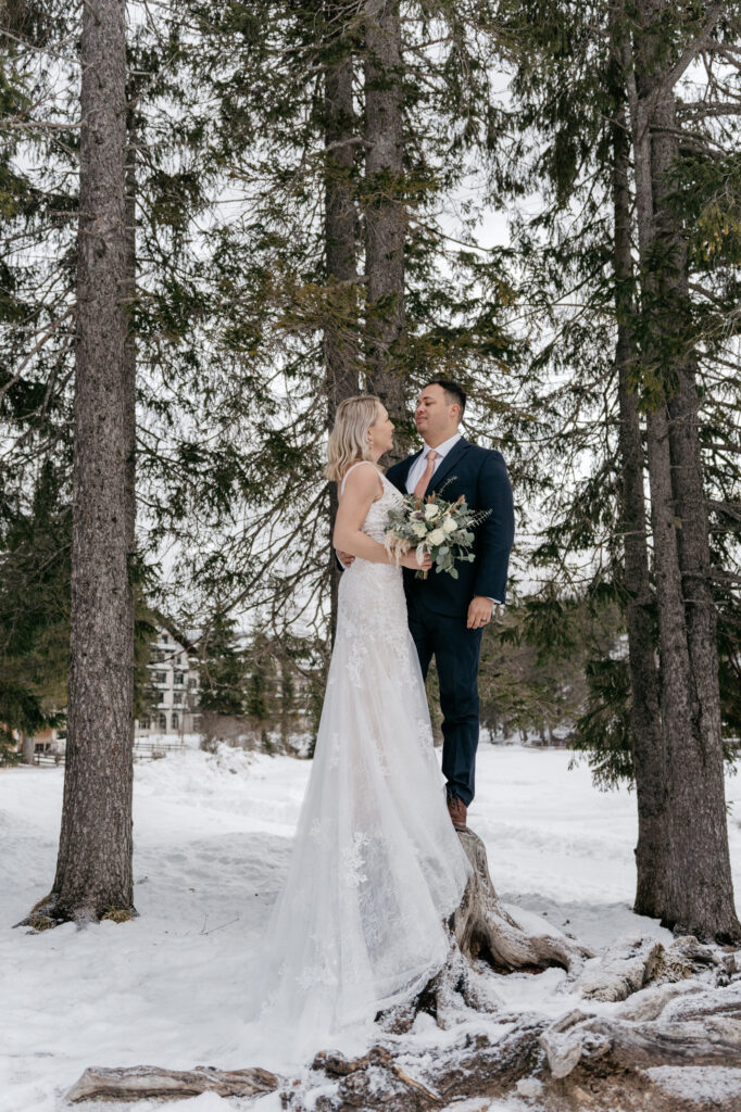 Bride and groom in snowy forest setting.