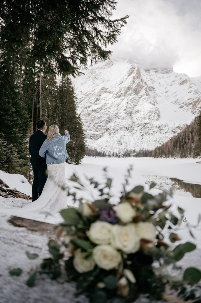 Couple in snowy mountain wedding scene with bouquet.