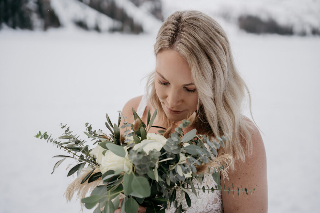 Bride holding bouquet with snowy background.