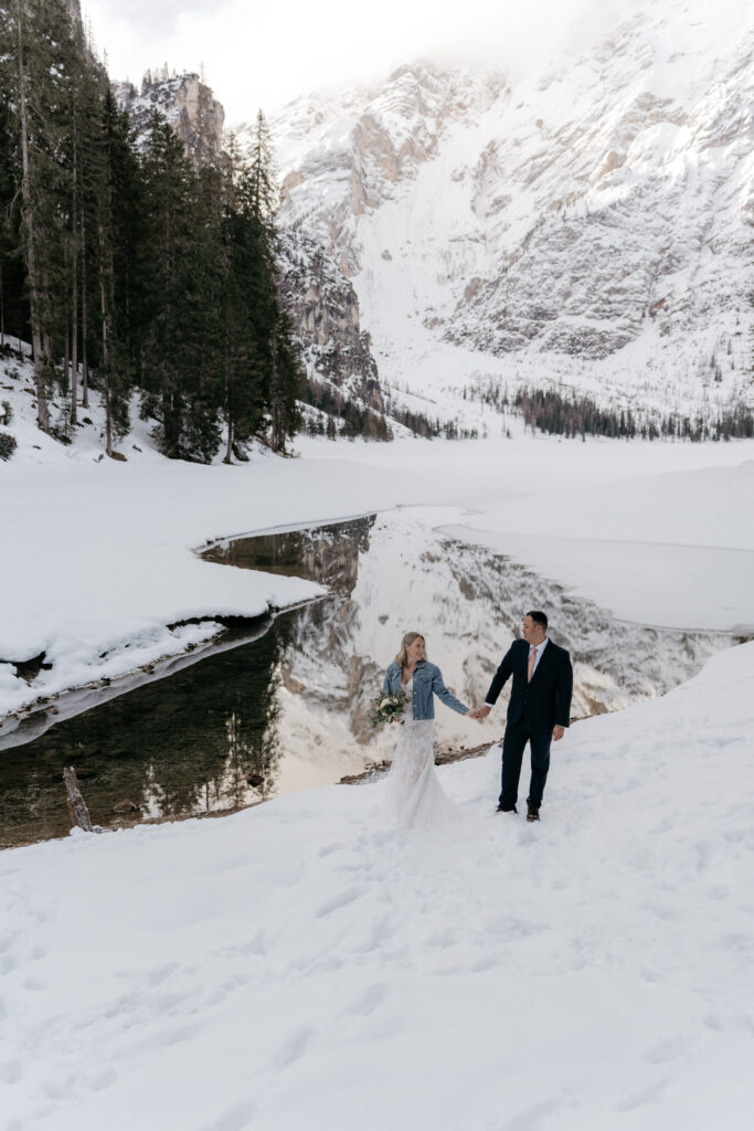 Couple holding hands in snowy mountain landscape.