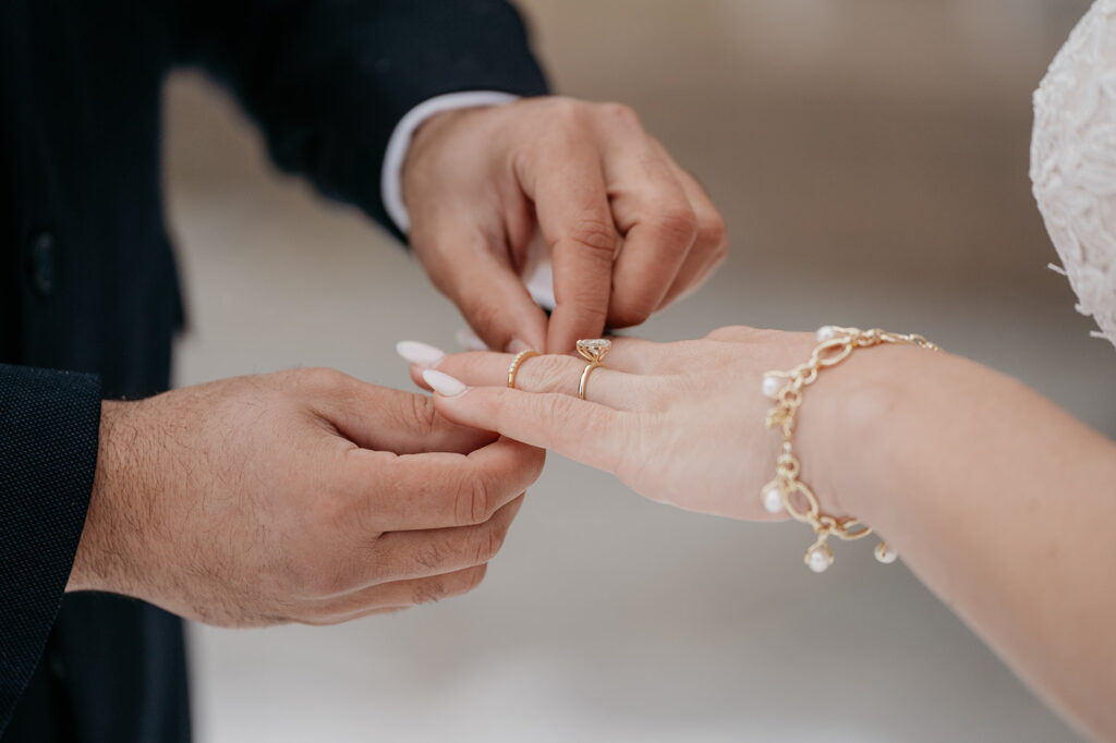 Placing wedding ring on bride's finger close-up.