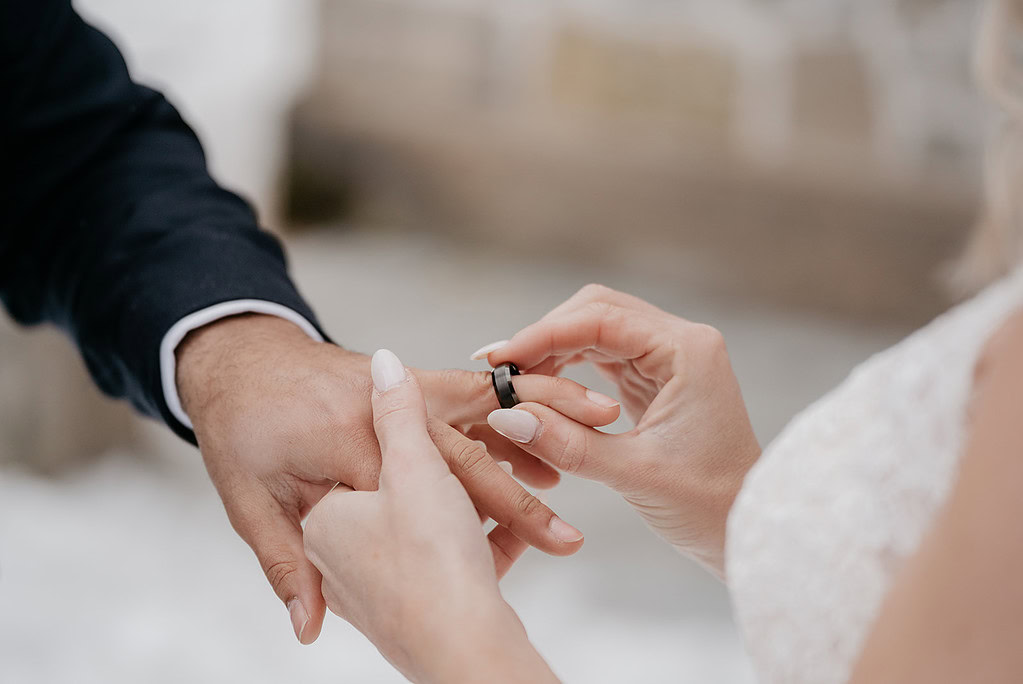 Bride places ring on groom's finger during ceremony.