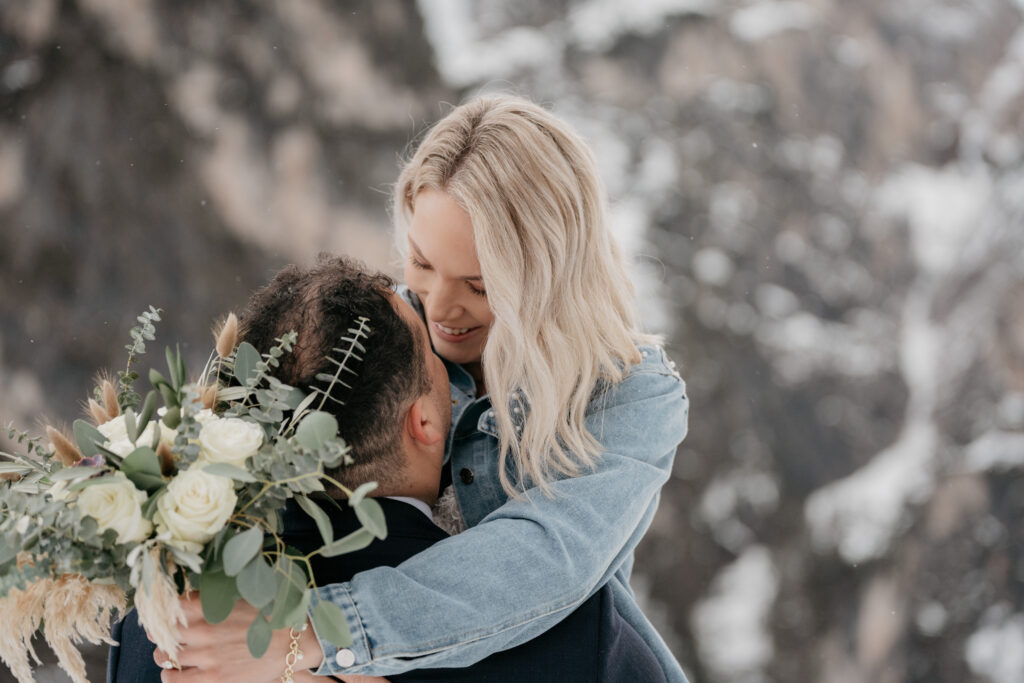 Couple embracing with bouquet, snowy background