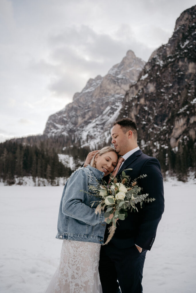 Couple embraces against snowy mountain backdrop.