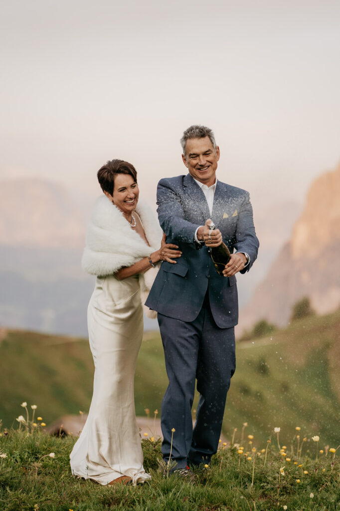 Couple celebrating outdoors with champagne in mountains.