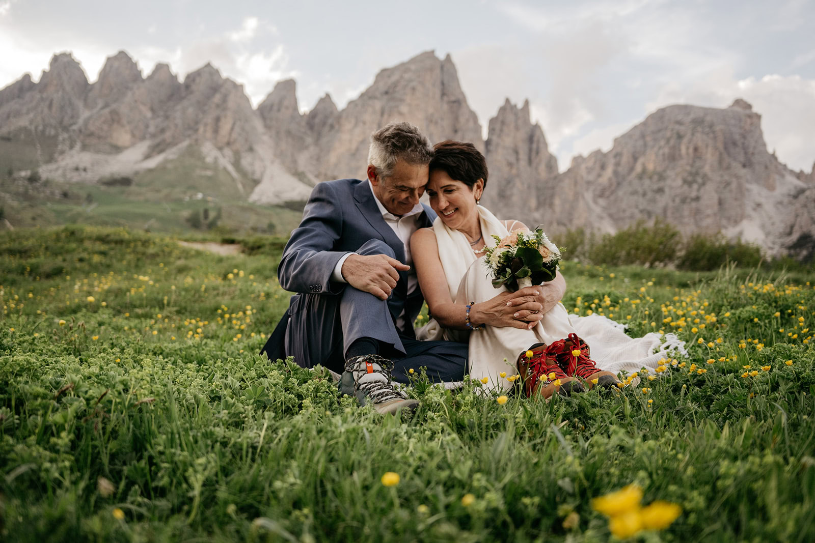 Couple sitting in mountain meadow with flowers.