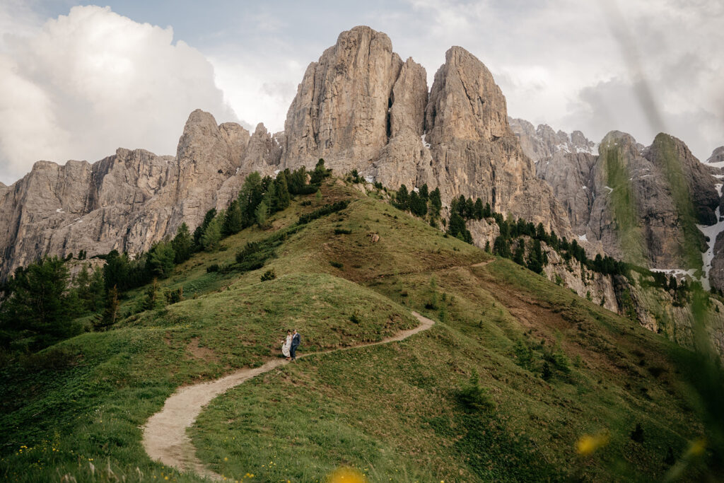 Mountain path with towering cliffs and greenery.