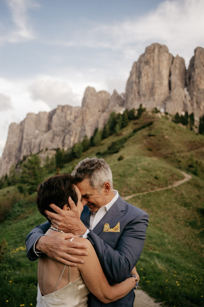 Couple embraces with mountain landscape background.