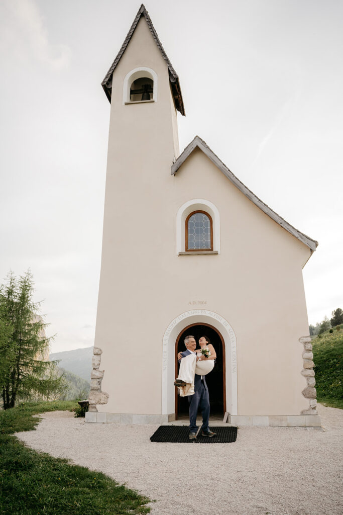 Couple at small church entrance, scenic background