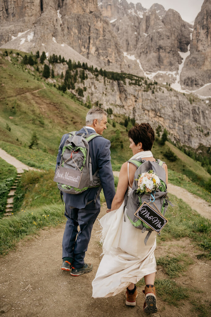 Newlyweds hiking with backpacks in mountains