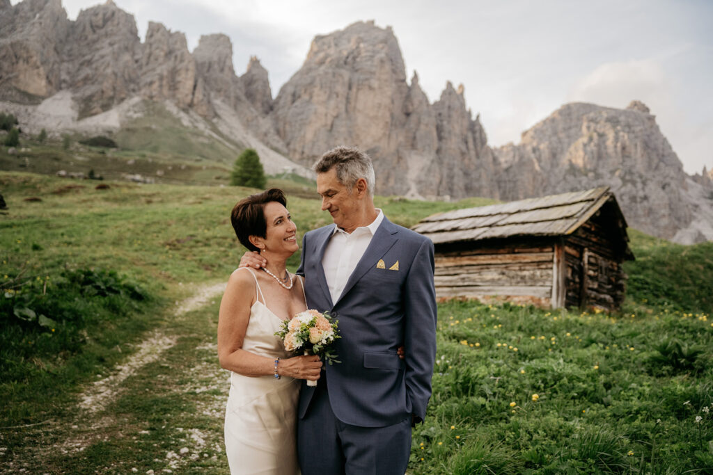 Couple embraces near mountain cabin in scenic landscape.