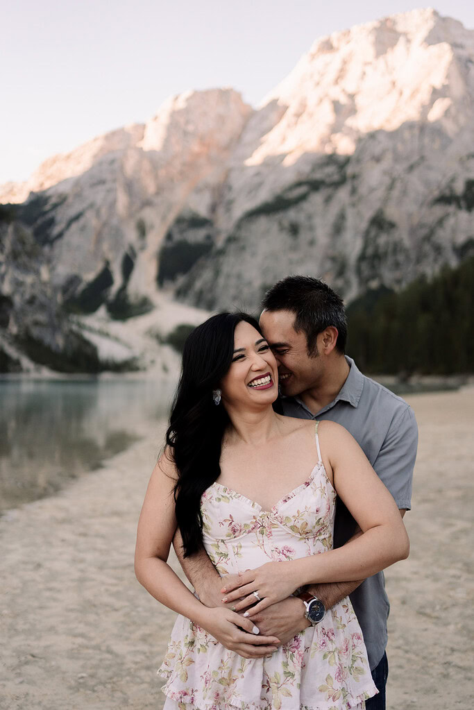 Couple embracing by mountain lake.