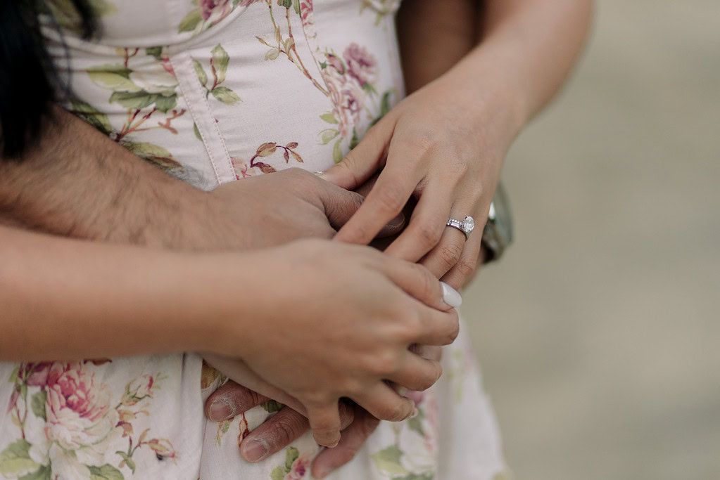 Close-up of couple holding hands with engagement ring