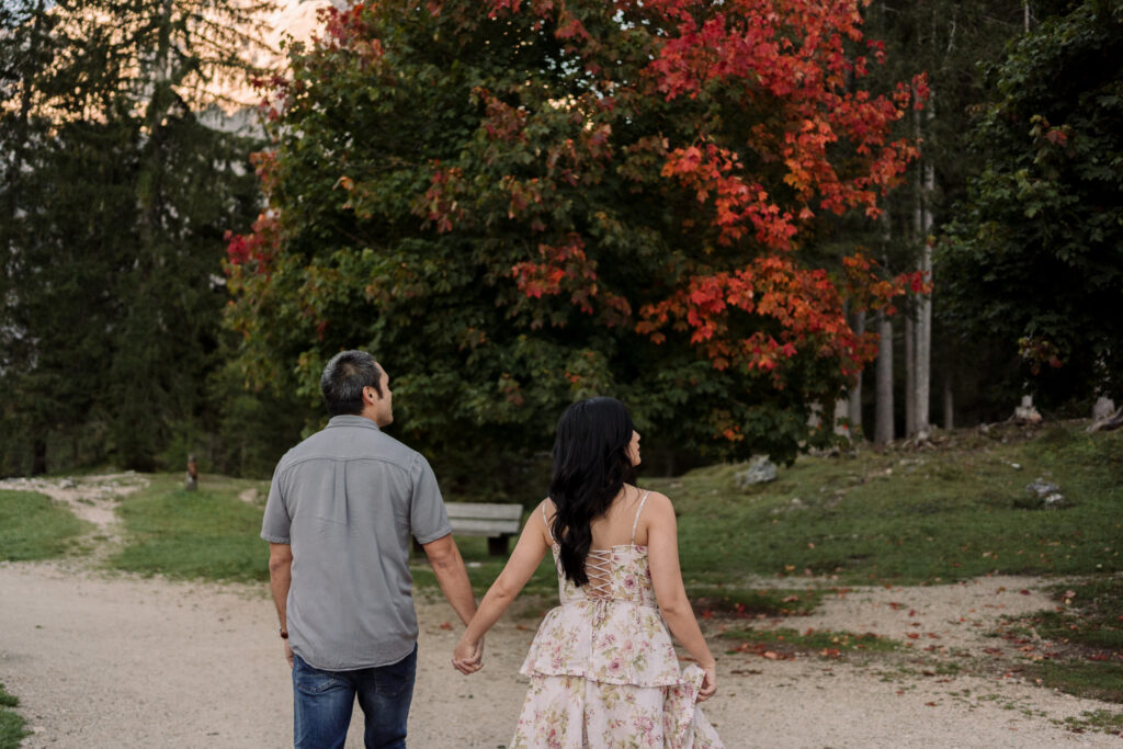 Couple walking on path, autumn trees in background.