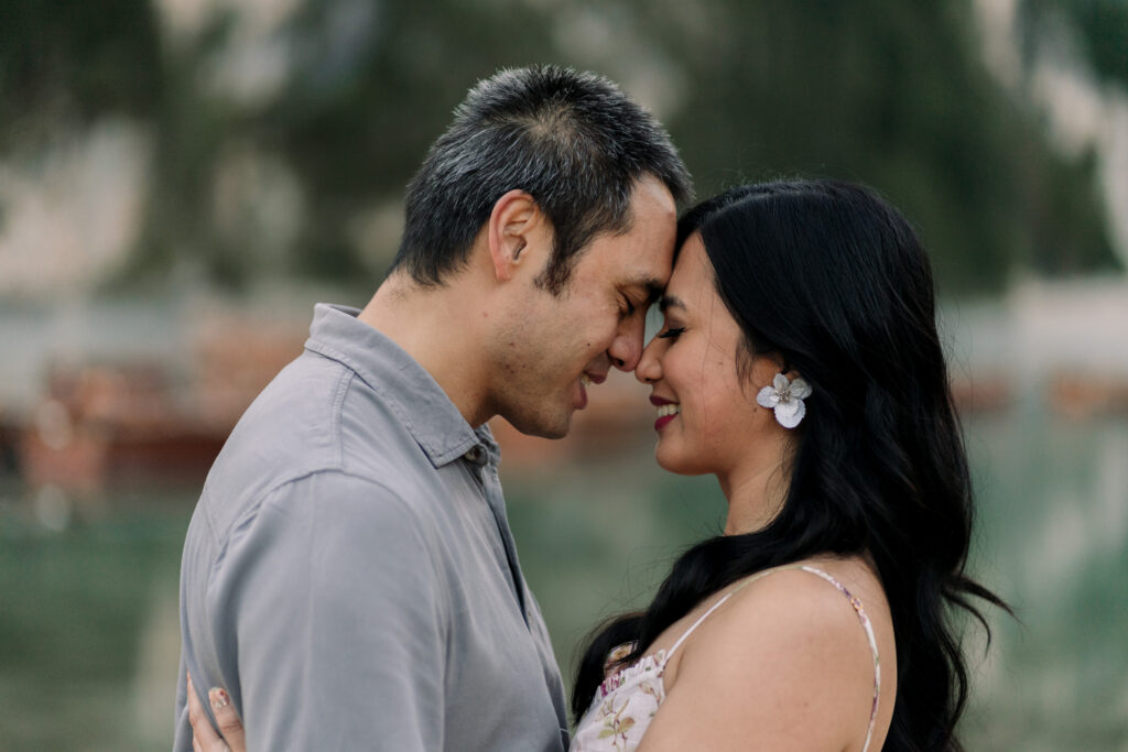 Couple touching foreheads, smiling outdoors.