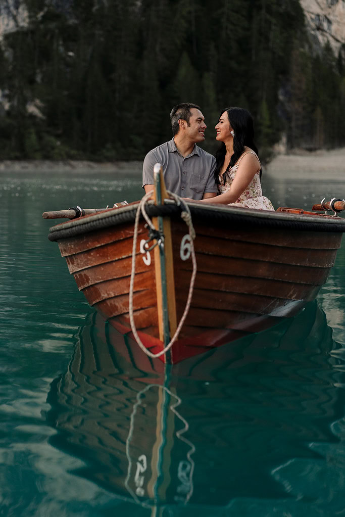 Couple sitting in a wooden boat on a lake.