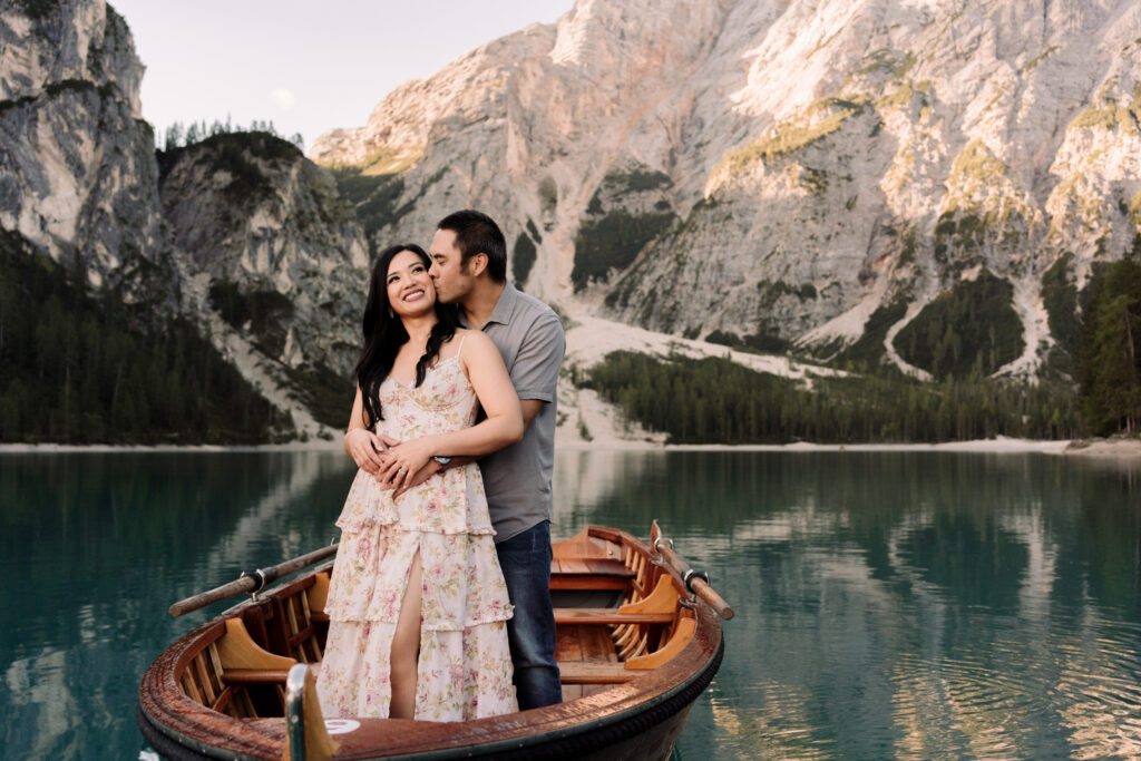 Couple embracing on boat in mountain lake scenery.