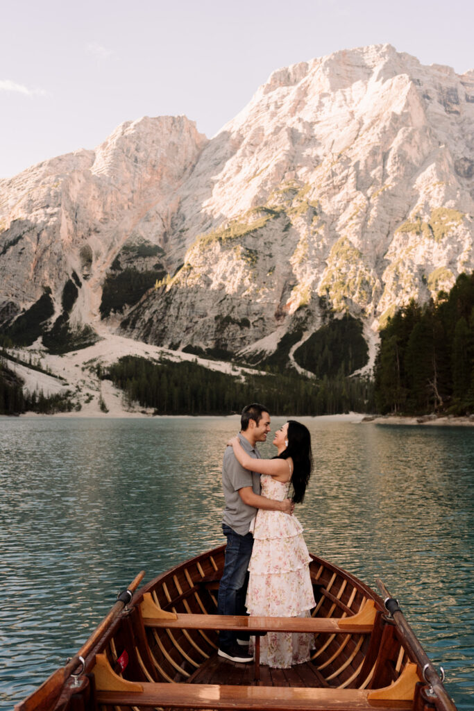 Couple embracing on boat with mountain backdrop.