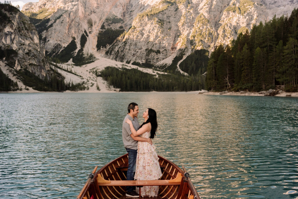 Couple embraces in boat on serene mountain lake.