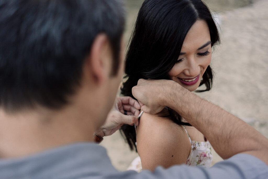 Man adjusting woman's dress strap outdoors.