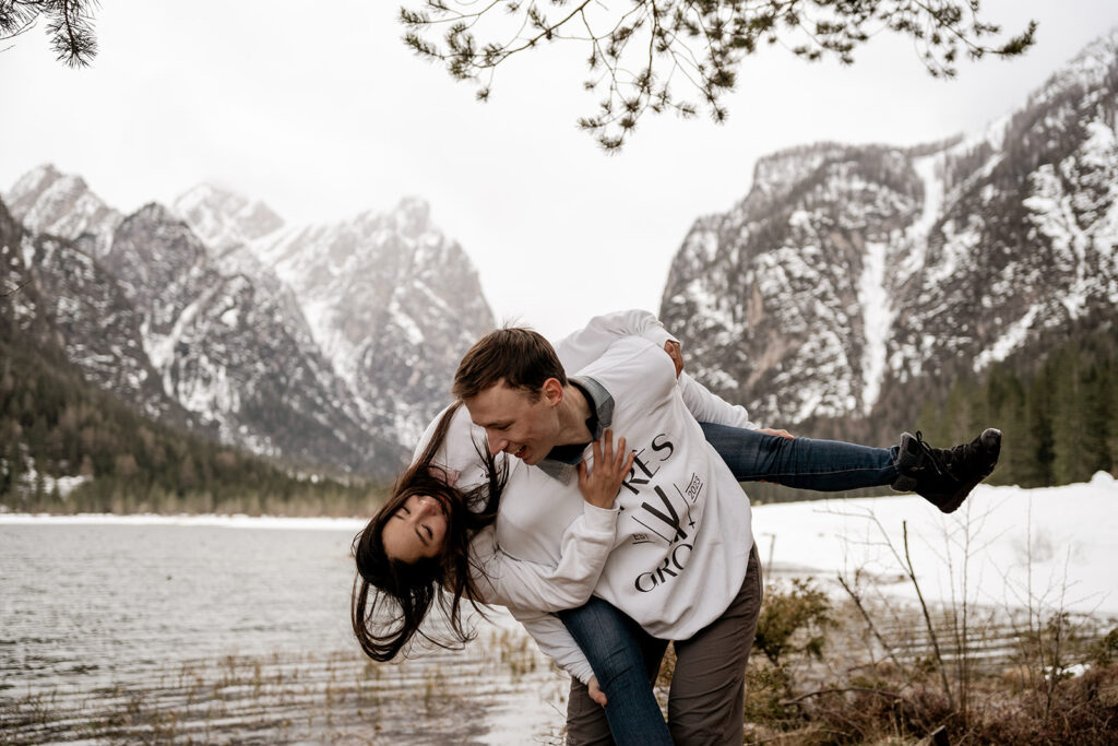 Couple playing near snowy mountain lake