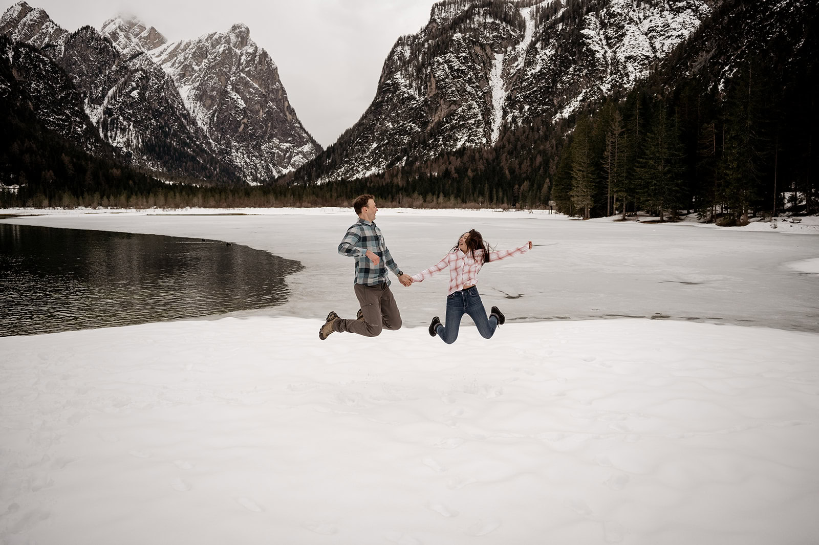 Couple jumping on snowy mountain landscape