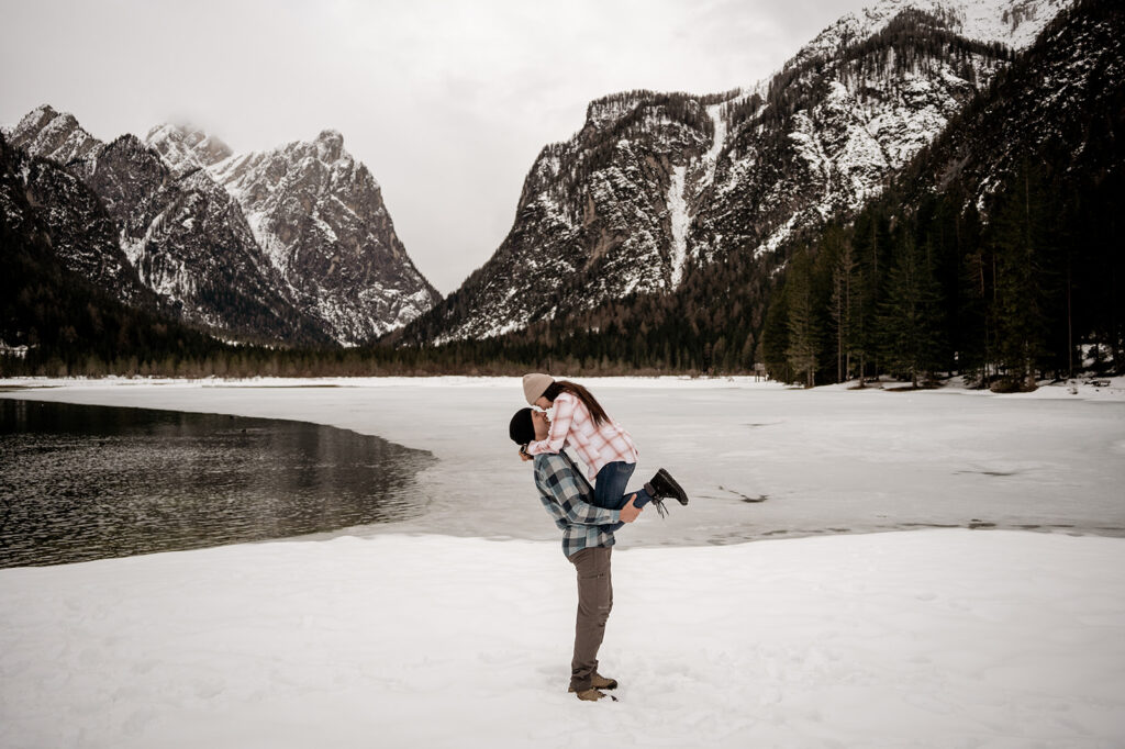 Couple embracing on snowy mountain landscape.