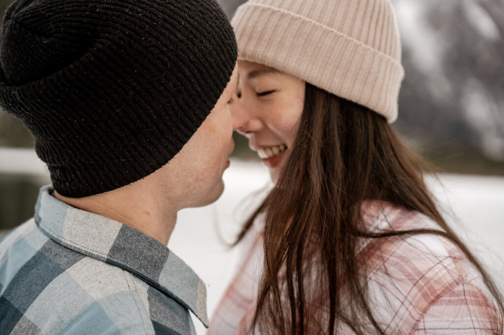 Couple smiling wearing winter hats outdoors.